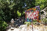 Bonita_Falls_062_06122020 - Julie walking by a graffiti-laced sign at the mouth of the canyon containing Bonita Falls