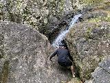 Canon_de_San_Cristobal_013_iPhone_04202022 - Ricardo scrambling among the slippery boulders towards a small cave with a regal view across the Charco Azul Waterfall in Canon de San Cristobal