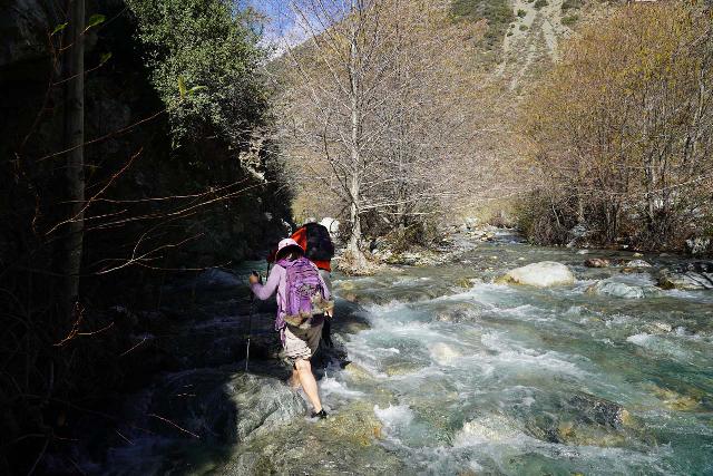 Mom in aquatic water shoes engaged in one of numerous river crossings on a long hike