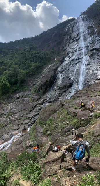 Do_Quyen_019_iPhone_04232025 - Looking out from my viewing spot of the Rhododendron Falls at a tour group (most of whom wore helmets) scrambling further down to a rope and then climbed up to a slab closer to the base of the waterfall's main drop