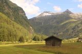 Hohe_Tauern_076_07152018 - Looking towards a lone barn or cabin fronting an attractive waterfall and mountain in the background well downhill from the Felbertauerntunnel toll station and Gasthaus Hohe Tauern