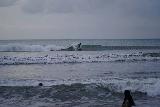 Kuta_068_06242022 - Looking towards a surfer riding a wave off of Kuta Beach
