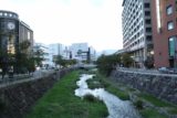 Matsumoto_009_10192016 - Looking from a road bridge towards a river flanked by modern buildings