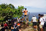 Nusa_Penida_047_06242022 - Context of some tour guides standing on tree branches to take elevated people shots that they've been queueing for at Kelingking Beach