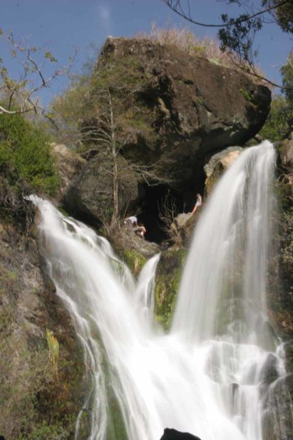 Salmon_Creek_Falls_040_03202010 - omhoog kijkend naar de top van Salmon Creek Falls waar mensen chillen tussen de convergerende segmenten van de waterval onder een reus's converging segments beneath a giant boulder