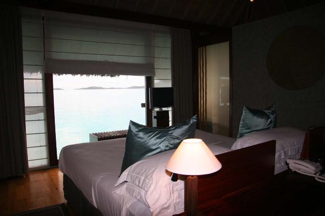 The bed has a direct view of the lagoon surrounding the overwater bungalow