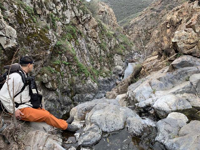 Mom in aquatic water shoes engaged in one of numerous river crossings on a long hike