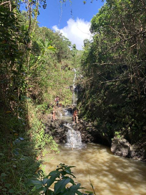 Waimano Falls and people using the rope swing above the intermediate cascade