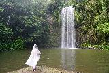 Waterfall_Circuit_034_06292022 - Tahia in a trash-bag-looking rain poncho standing across the plunge pool before Millaa Millaa Falls